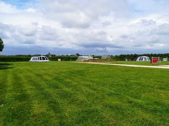 The back field, with tents pitched on open grass under a cloudy sky